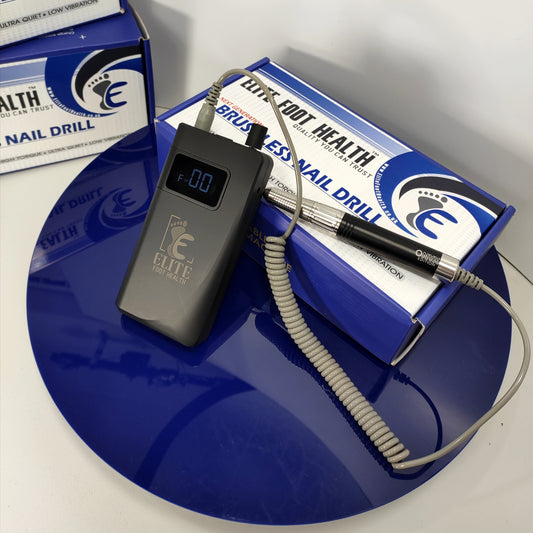 A black mobile podiatry nail drill with a numerical display screen, accompanied by a power cord and resting on a blue surface. Product packaging is visible in the background.