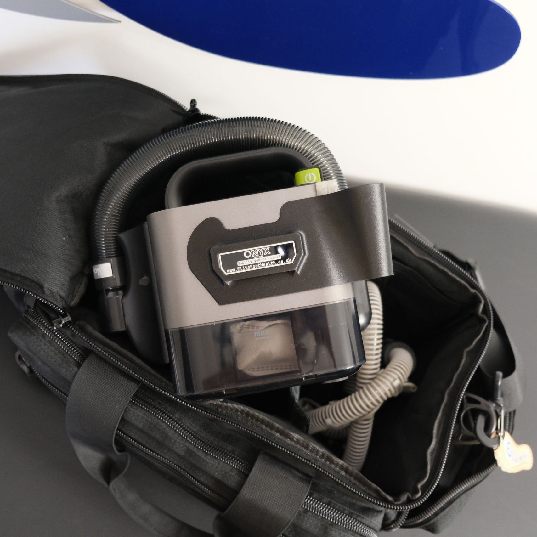 Portable oxygen concentrator in a black carrying case with a blue top.