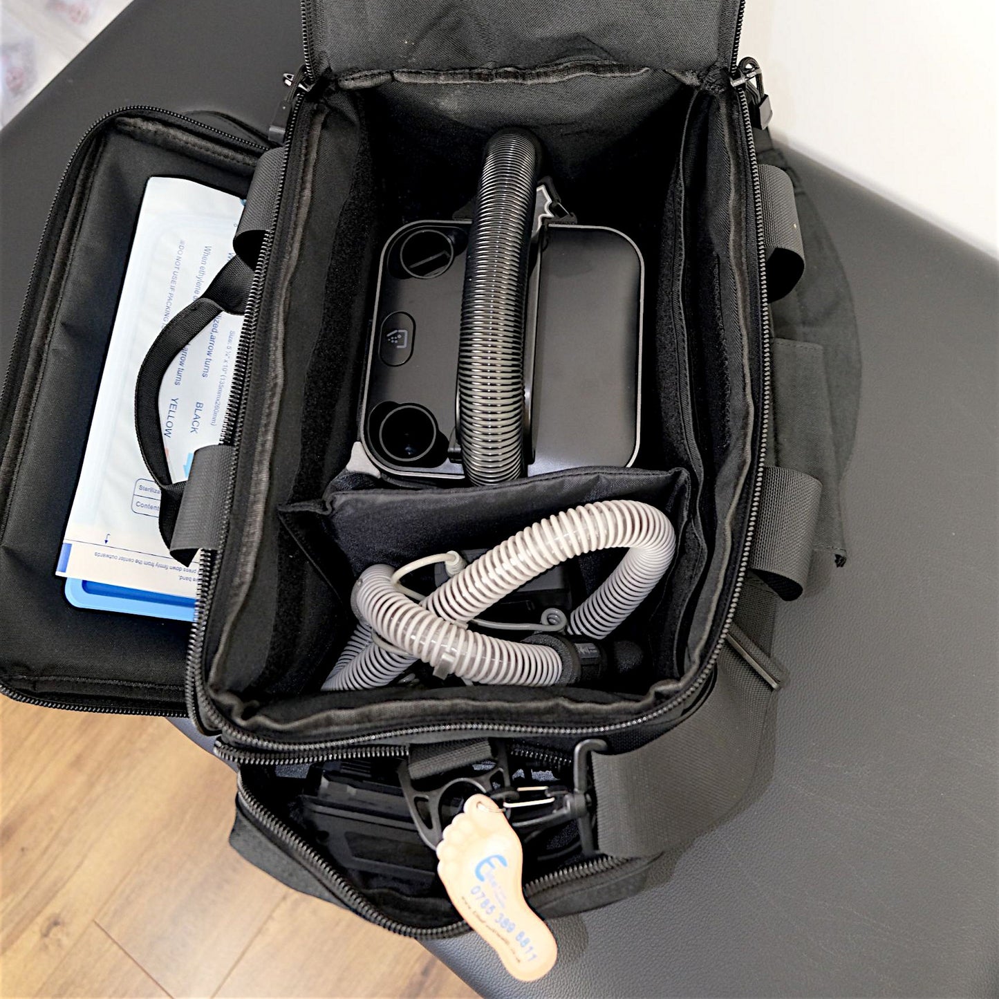 Black travel bag with medical equipment on a wooden floor